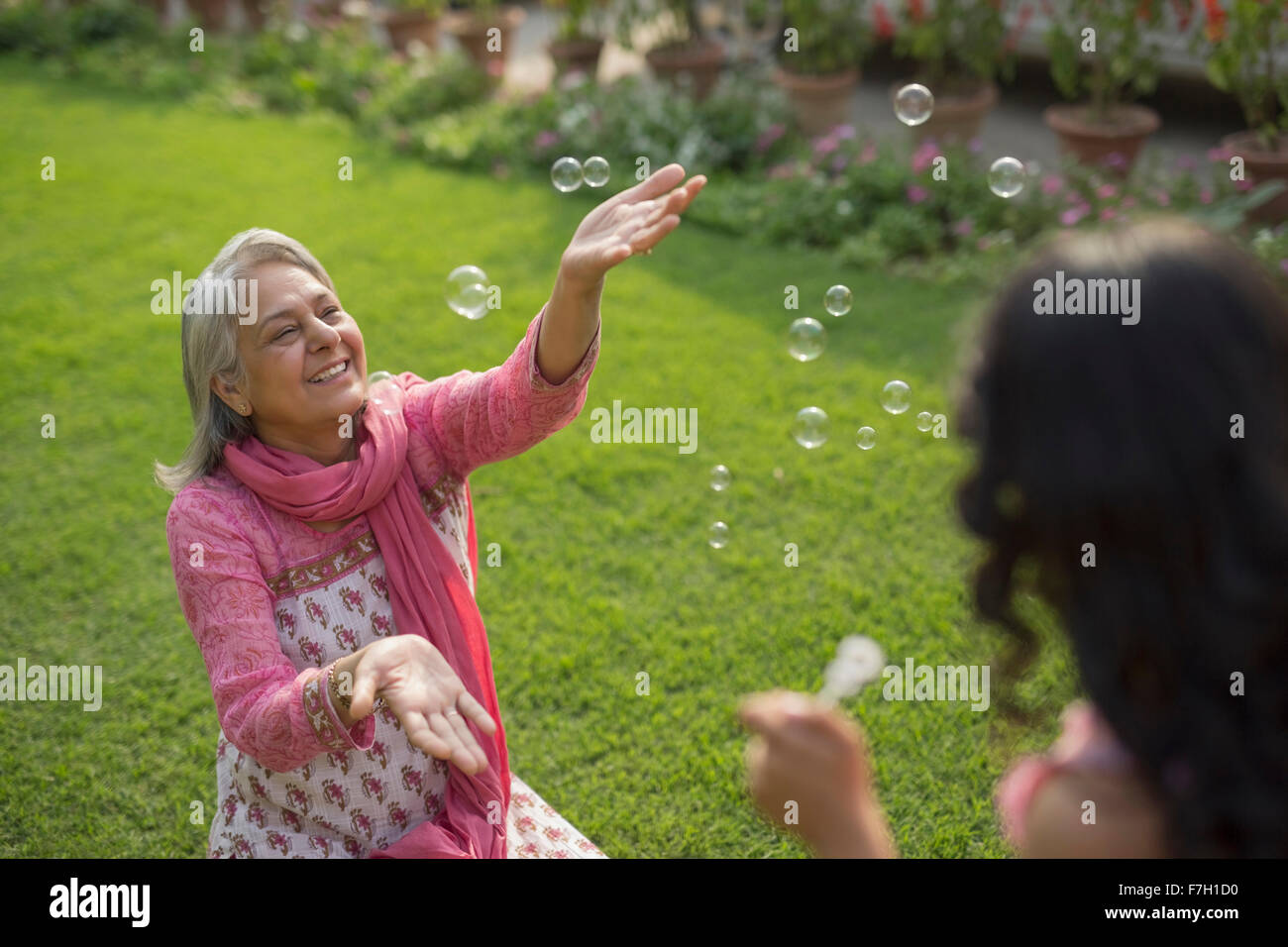 Grandmother catching bubbles with granddaughter (4-5) Stock Photo