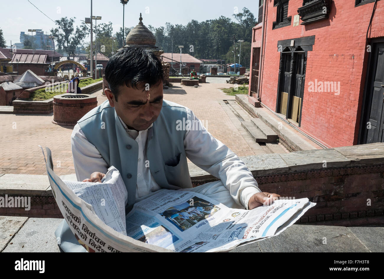 a middle aged Nepali man reading newspaper at Pashupatinath, Kathmandu, 2015, Nepal Stock Photo