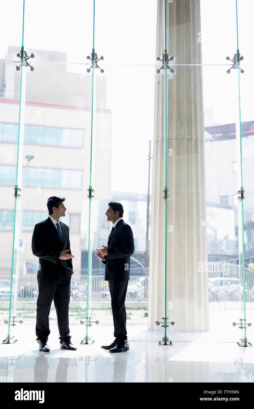 India, Two businessmen in suits talking in glass office lobby Stock ...