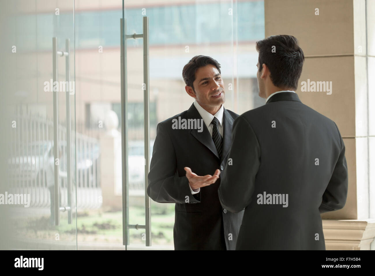 India, Two businessmen talking in office lobby Stock Photo - Alamy