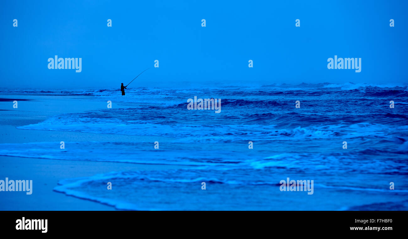 Lone fisherman, surf fishing on beach, late evening, K'gari Stock Photo