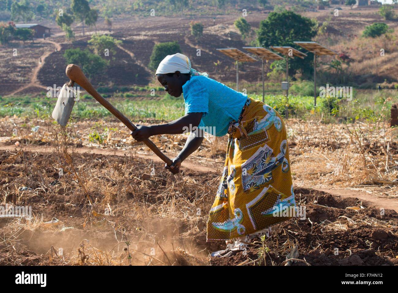 MALAWI, village Zingiziwa, woman prepare field with hoe, behind solar powered water pump for irrigation and water supply in village Stock Photo
