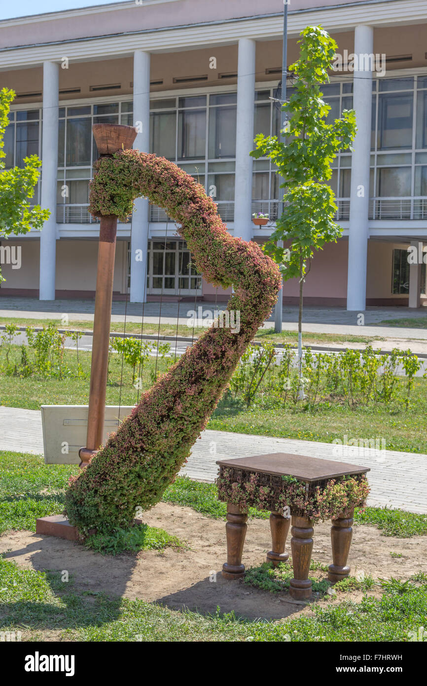 green topiary statue of a harp with stool Stock Photo