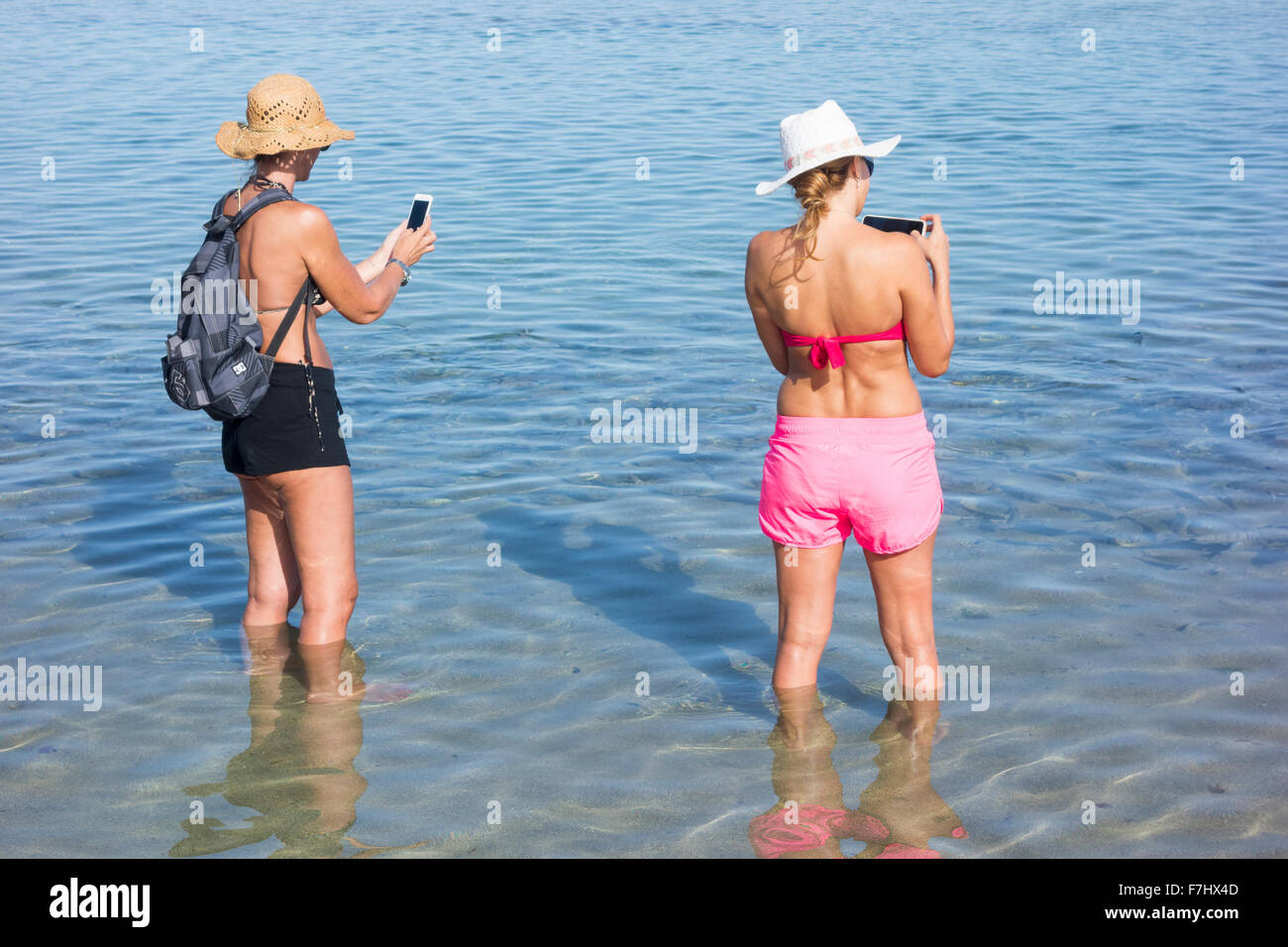 Two young female tourists taking selfies on beach Stock Photo