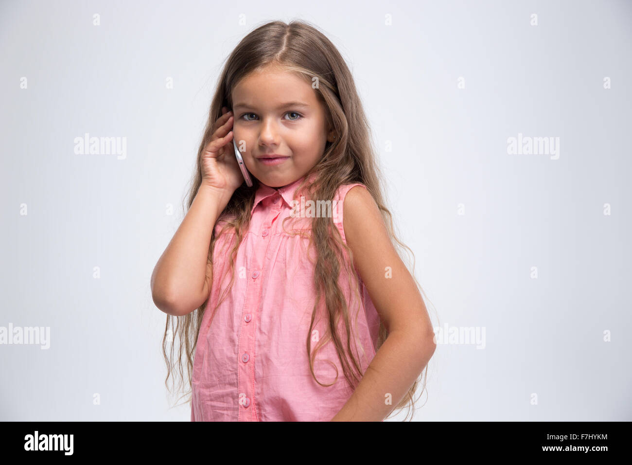 Portrait of a happy little girl talking on the phone isolated on a ...