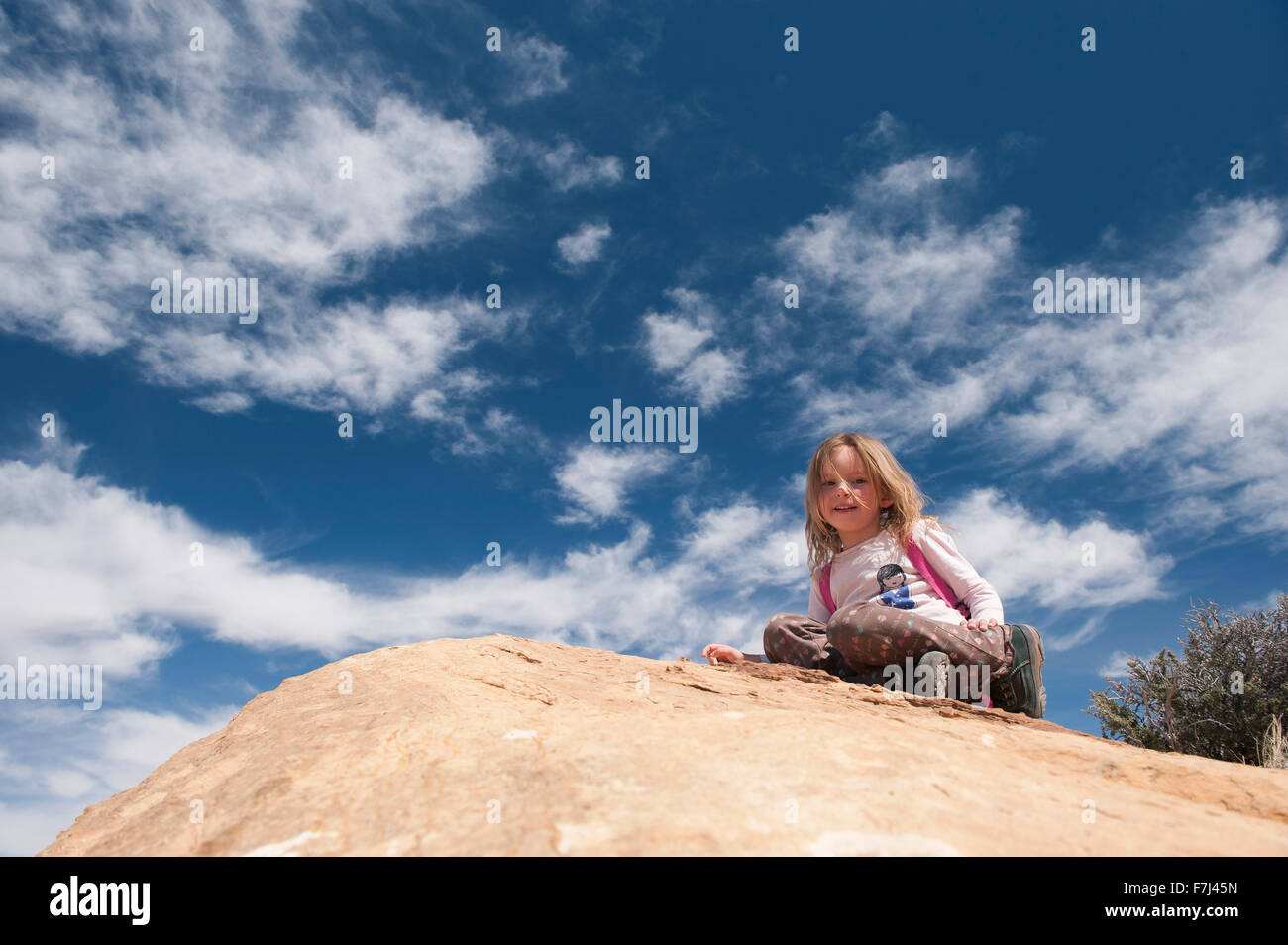 Little girl sitting on top of rock, portrait Stock Photo