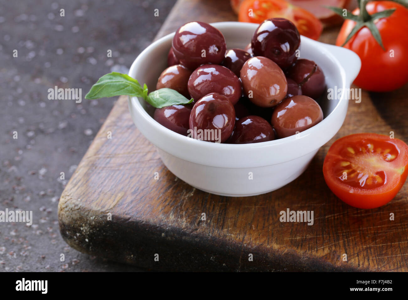 Italian food still life - olives, tomatoes, basil, prosciutto ham Stock Photo