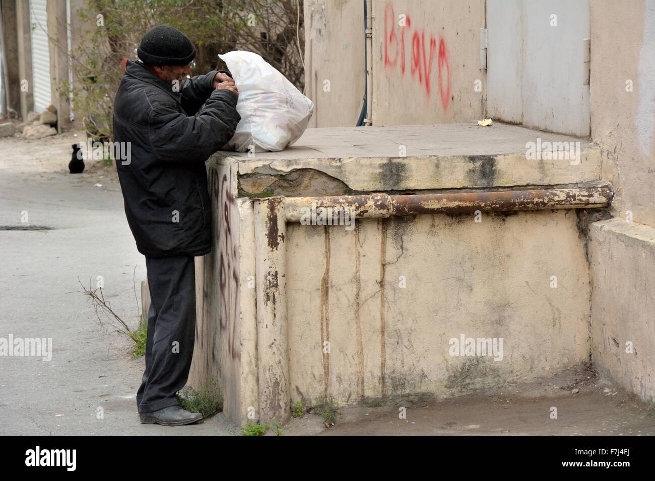 BAKU, AZERBAIJAN - 14 NOVEMBER 2013 Homeless man looking for food in rubbish in Baku, capital of Azerbaijan Stock Photo