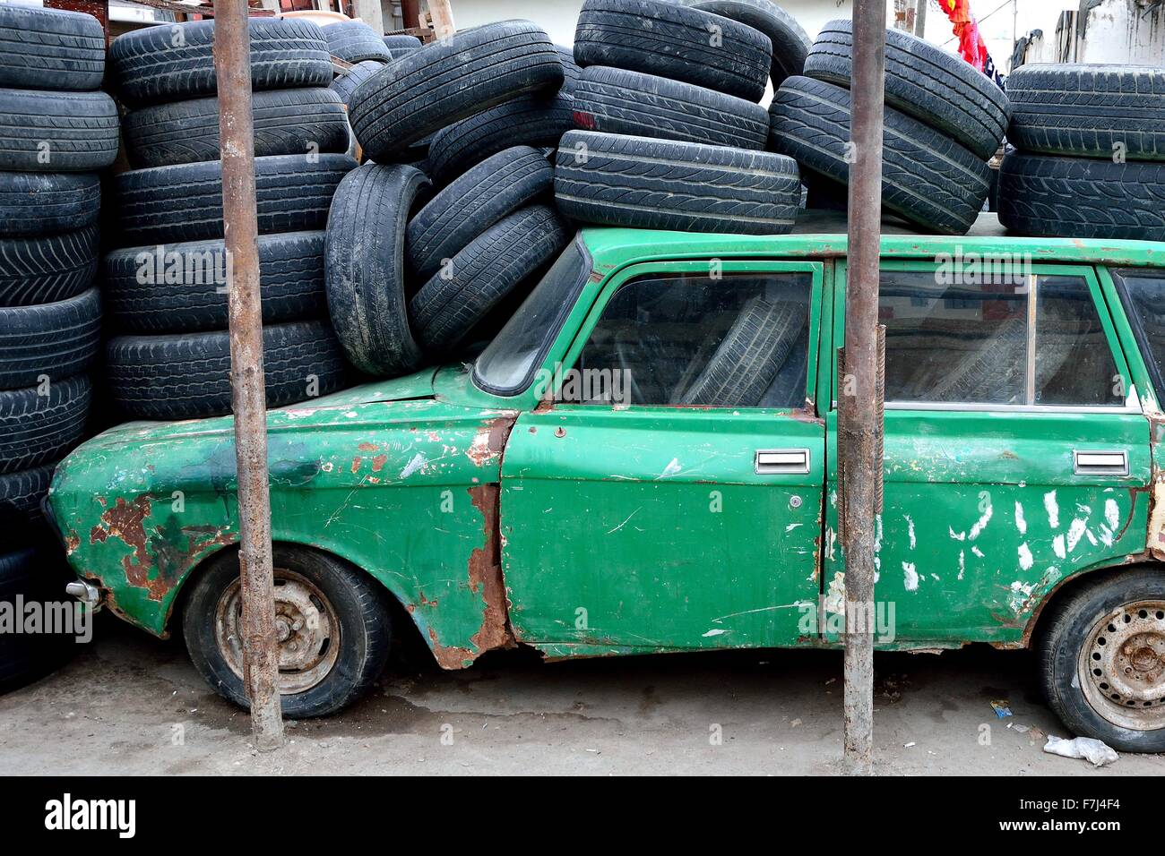 Old green Azerbaijani car in Baku, under a pile of tyres, from the side Stock Photo