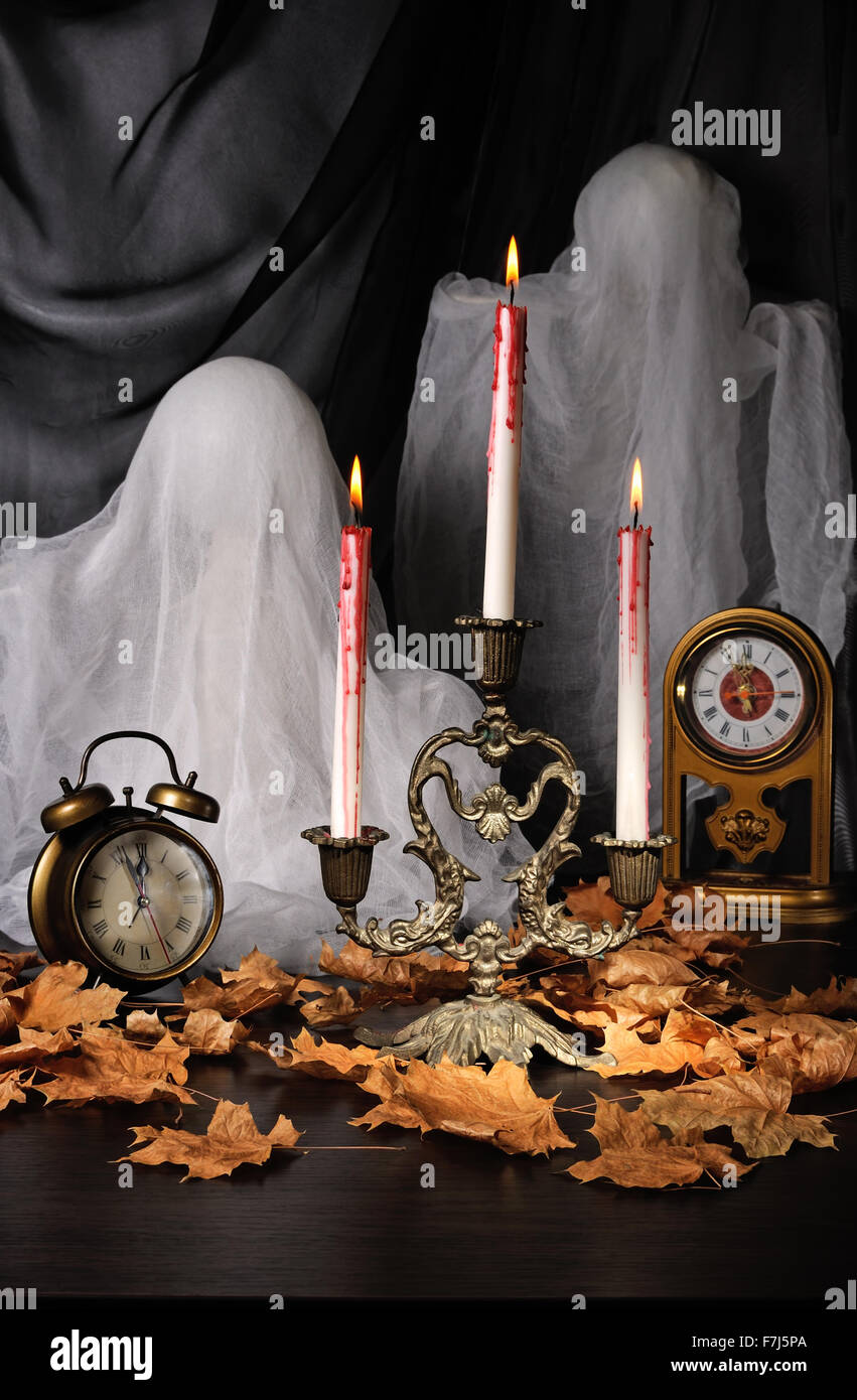 Candles among the fallen leaves with a clock and ghosts Stock Photo Alamy