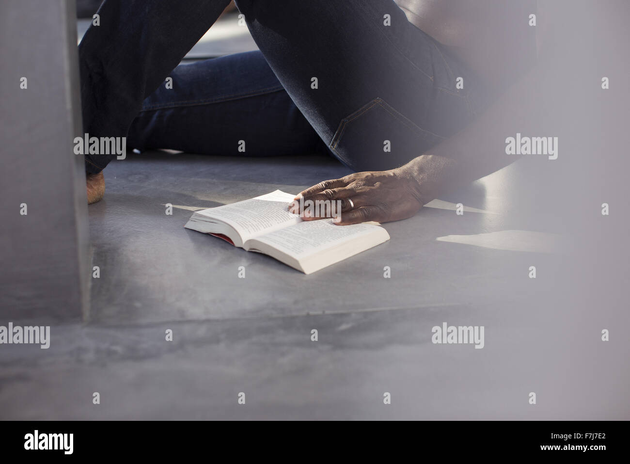 Man reading book on floor, cropped Stock Photo