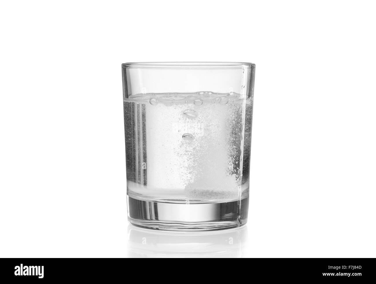 Glass with efervescent tablet in water. Isolated on white. Stock Photo