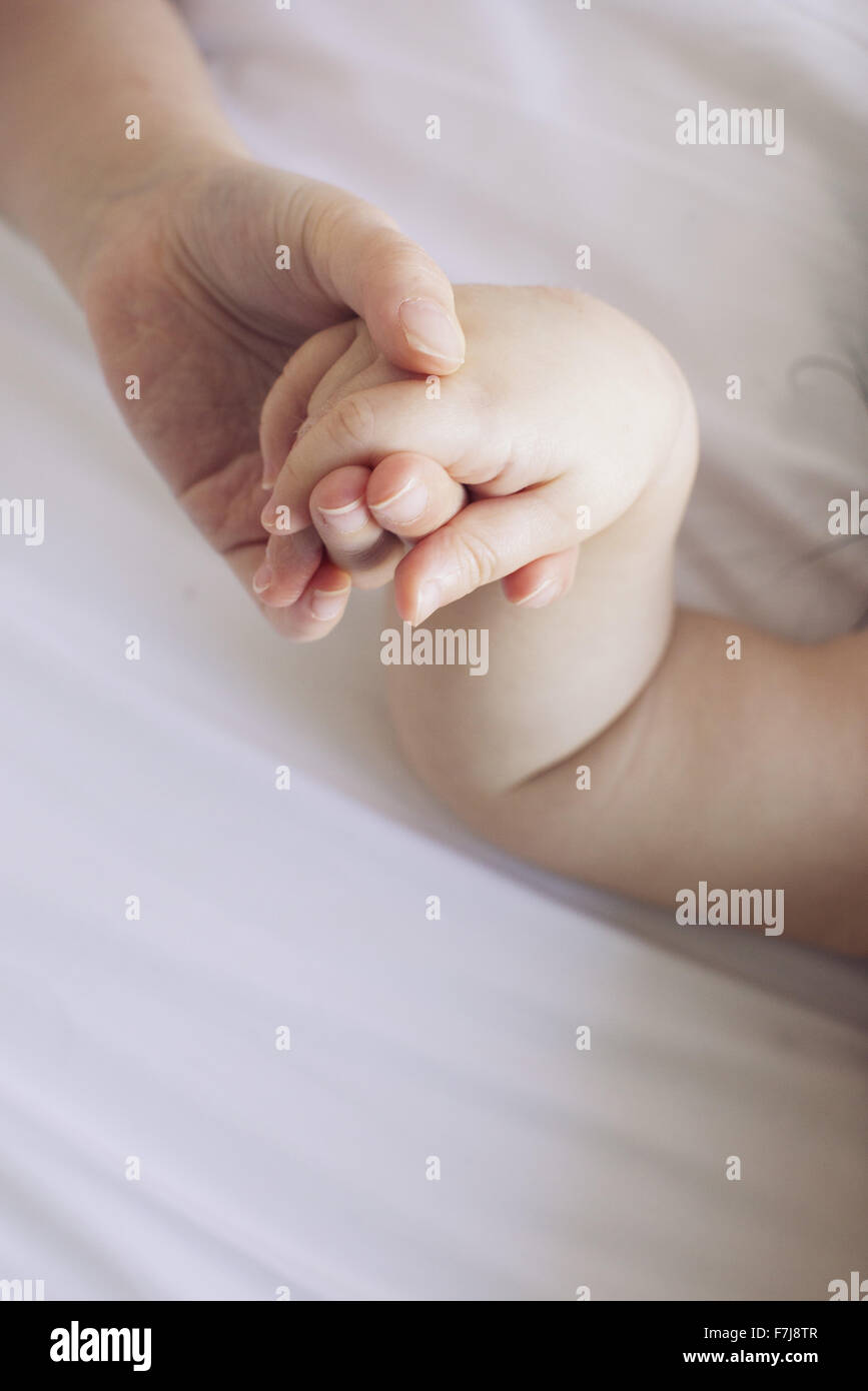 Child's hand holding baby's hand Stock Photo