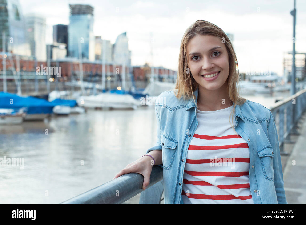 Young woman leaning against railing, smiling, portrait Stock Photo