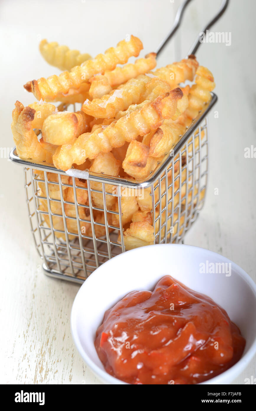 Crispy French Fries in a wire fryer basket with a spicy red pepper aoli