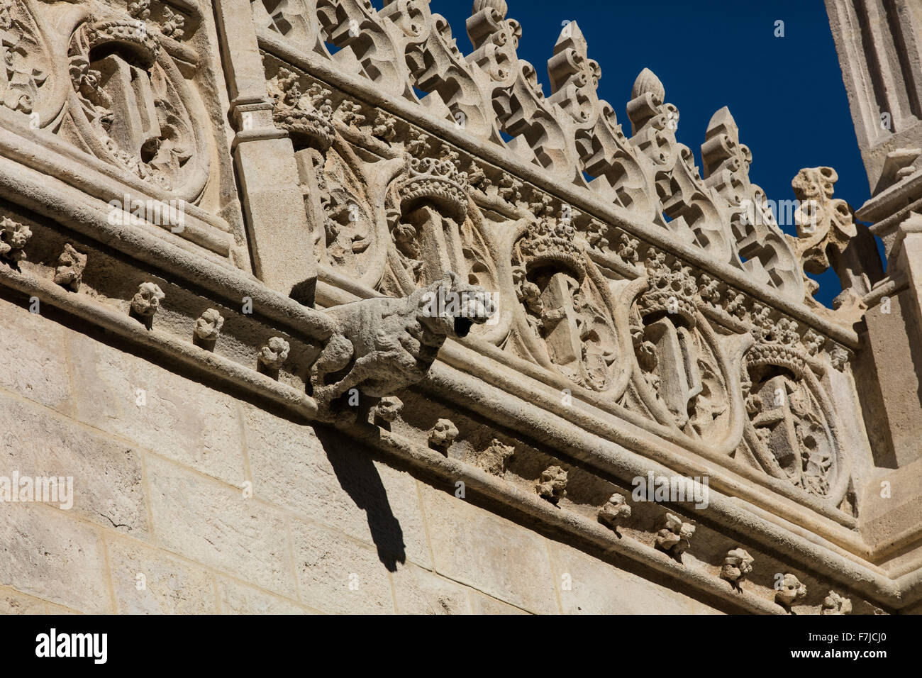 Gargoyle on the wall of Granada Cathedral with stone architecture on the roof above Stock Photo