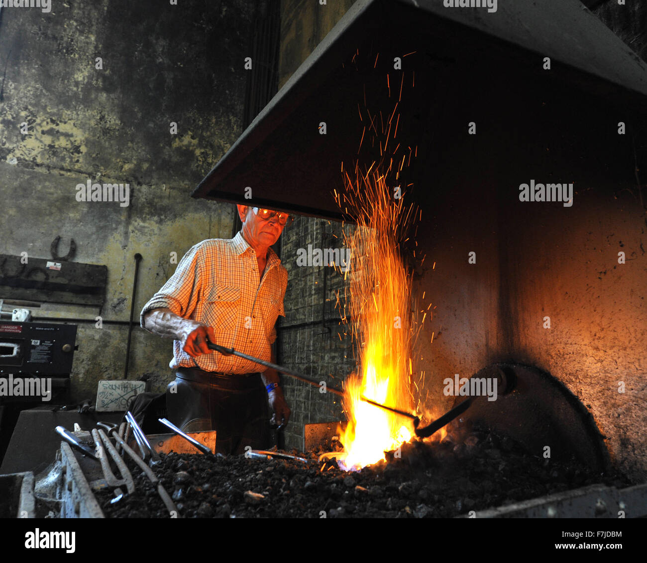 Farrier at work on horse shoe in forge Stock Photo