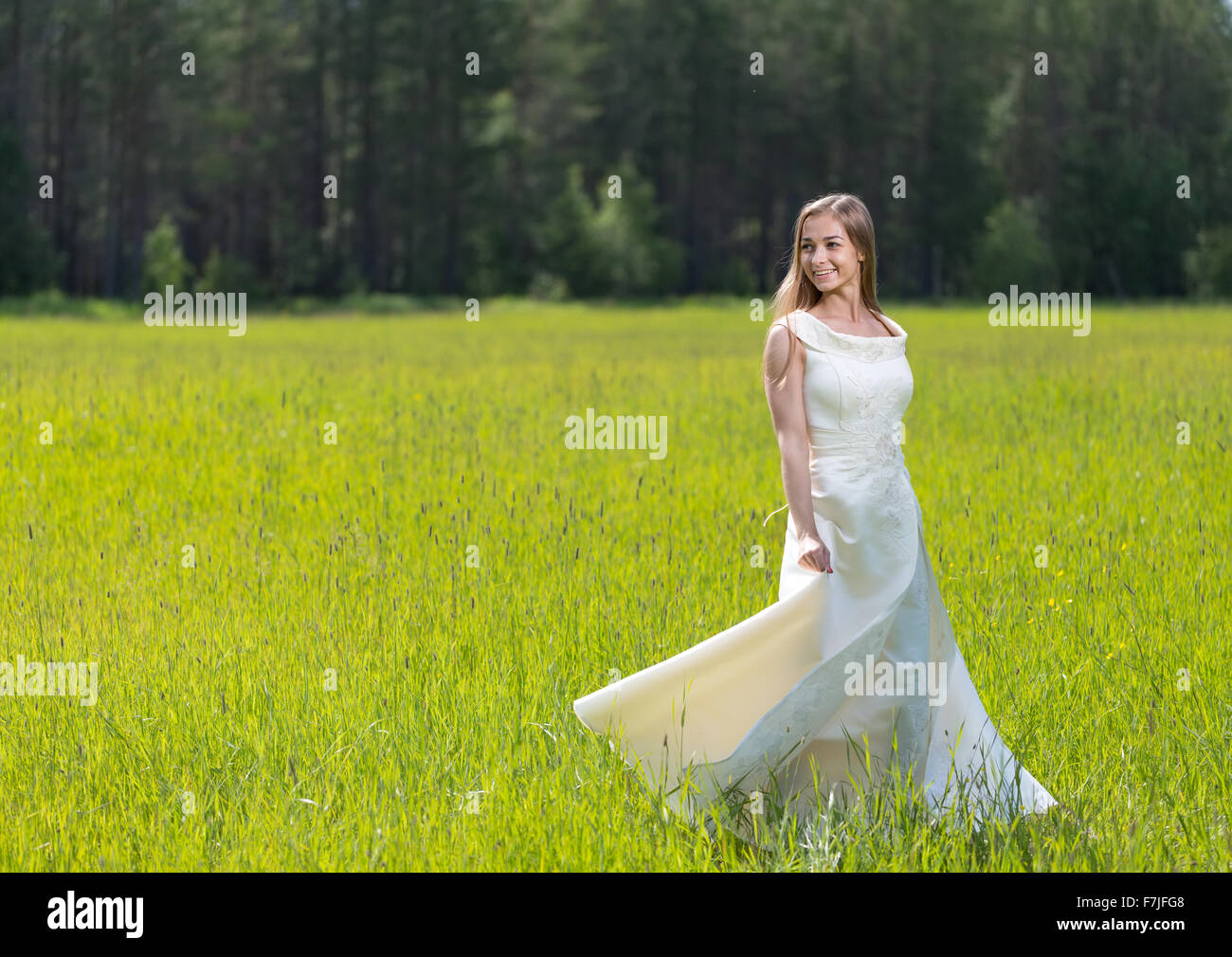 Young smiling woman in white dress standing in field Stock Photo - Alamy