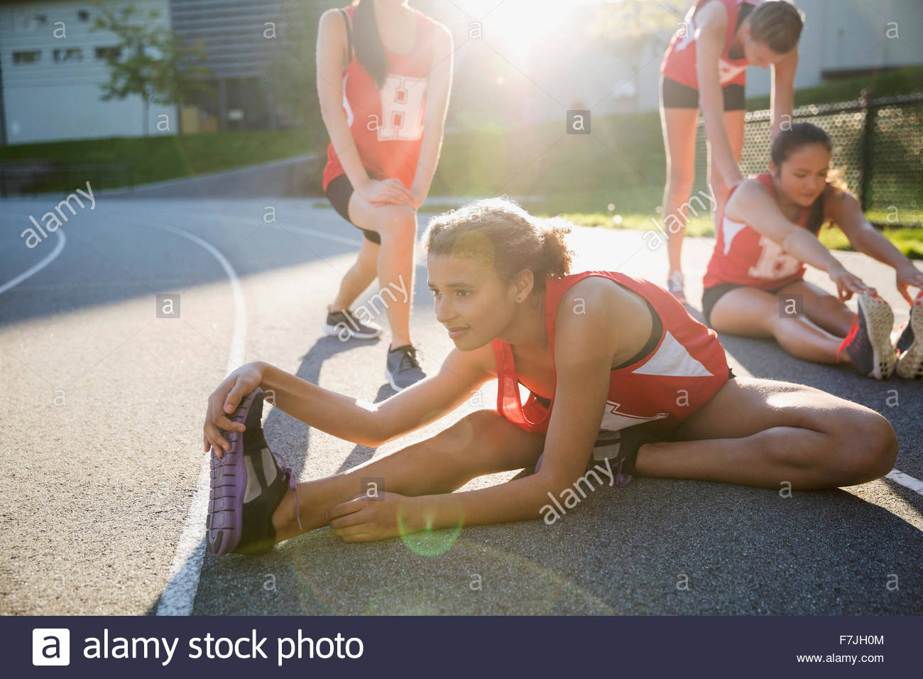 High school athlete stretching leg on running track Stock Photo