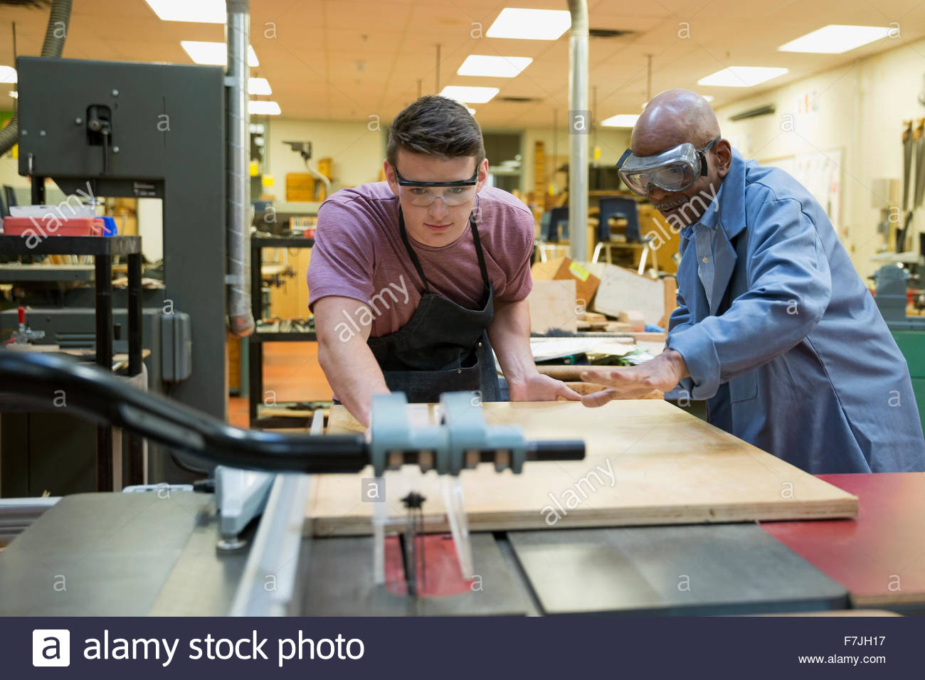 High school teacher guiding student at woodcutting machine Stock Photo