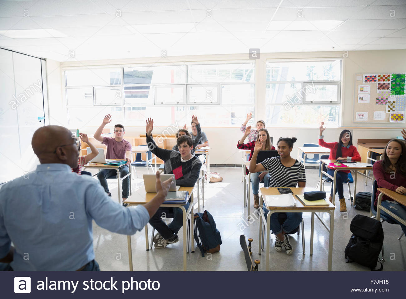 High school teacher calling students with hand raised Stock Photo