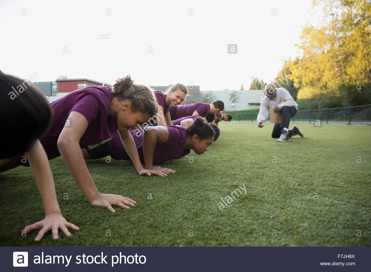 Physical education teacher encouraging students doing pushups Stock