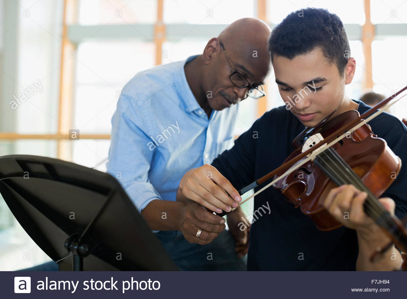 High school teacher helping student playing violin Stock Photo Alamy