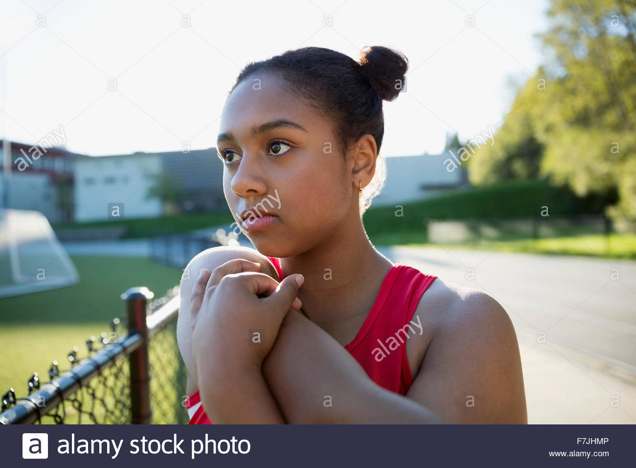 Determined high school athlete stretching arm running track Stock Photo