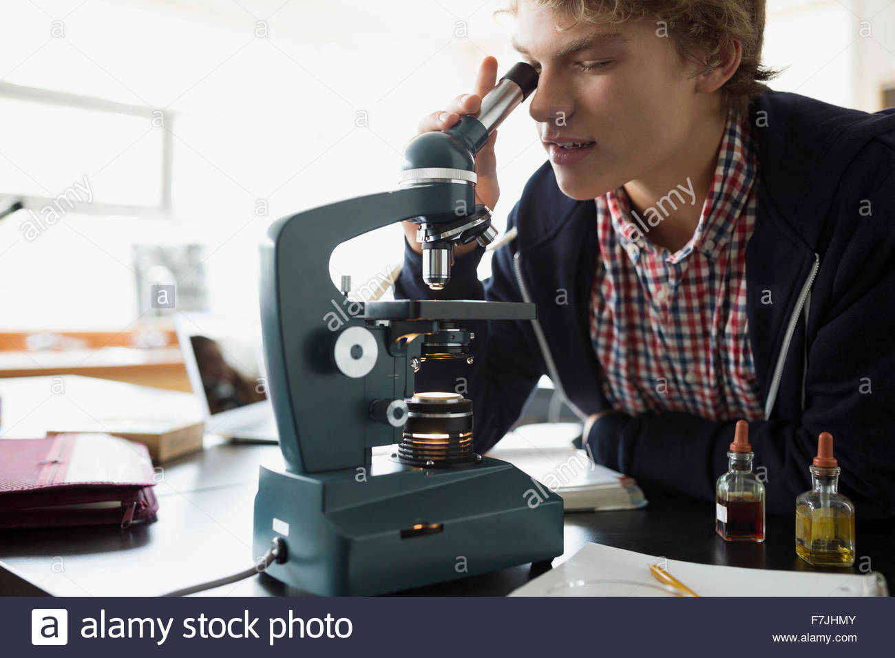 High school student using microscope science laboratory classroom Stock