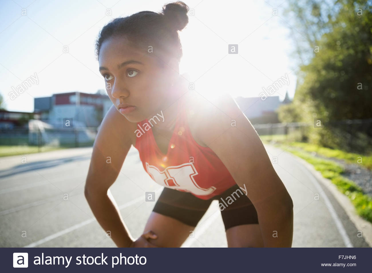 Serious high school athlete hands knees running track Stock Photo