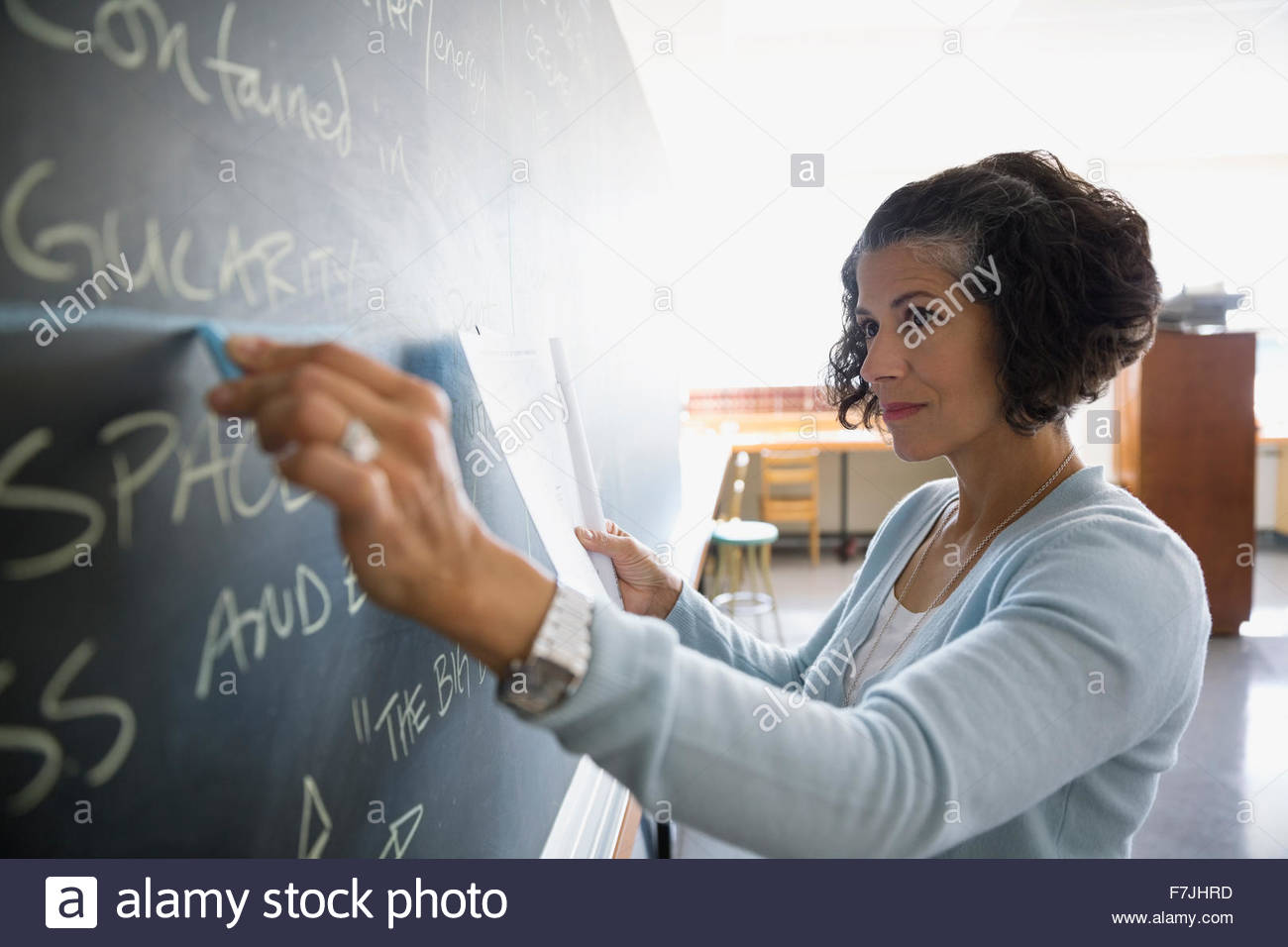 Teacher writing on blackboard in classroom Stock Photo