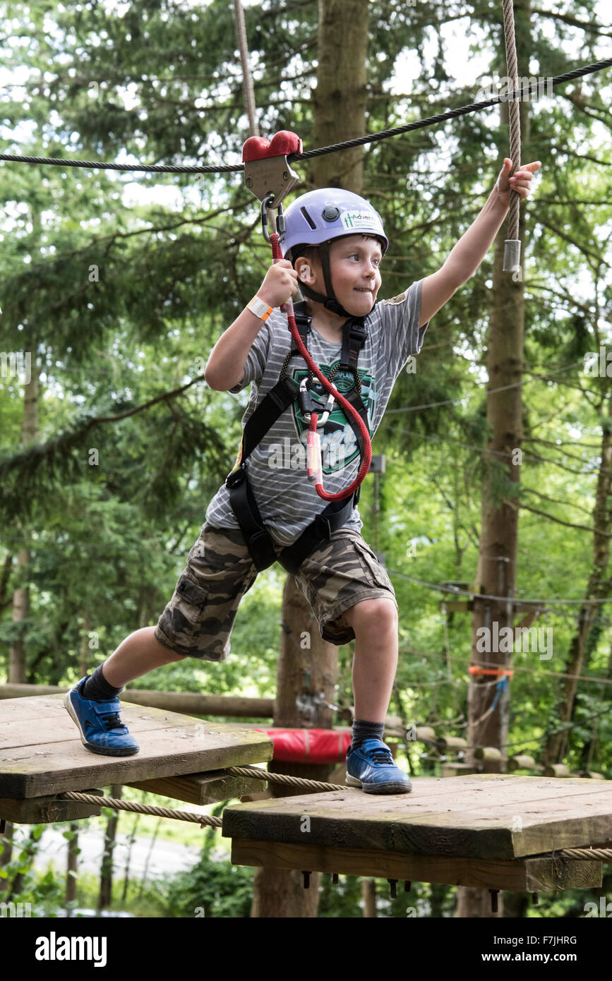 A look of determination on this boys face as he makes his way across the platforms up in the trees at the Treetops Adventure Stock Photo