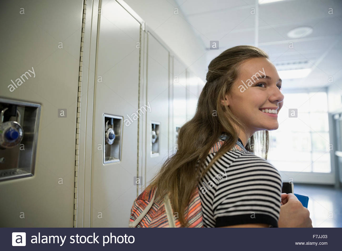 Smiling high school student looking over shoulder lockers Stock Photo