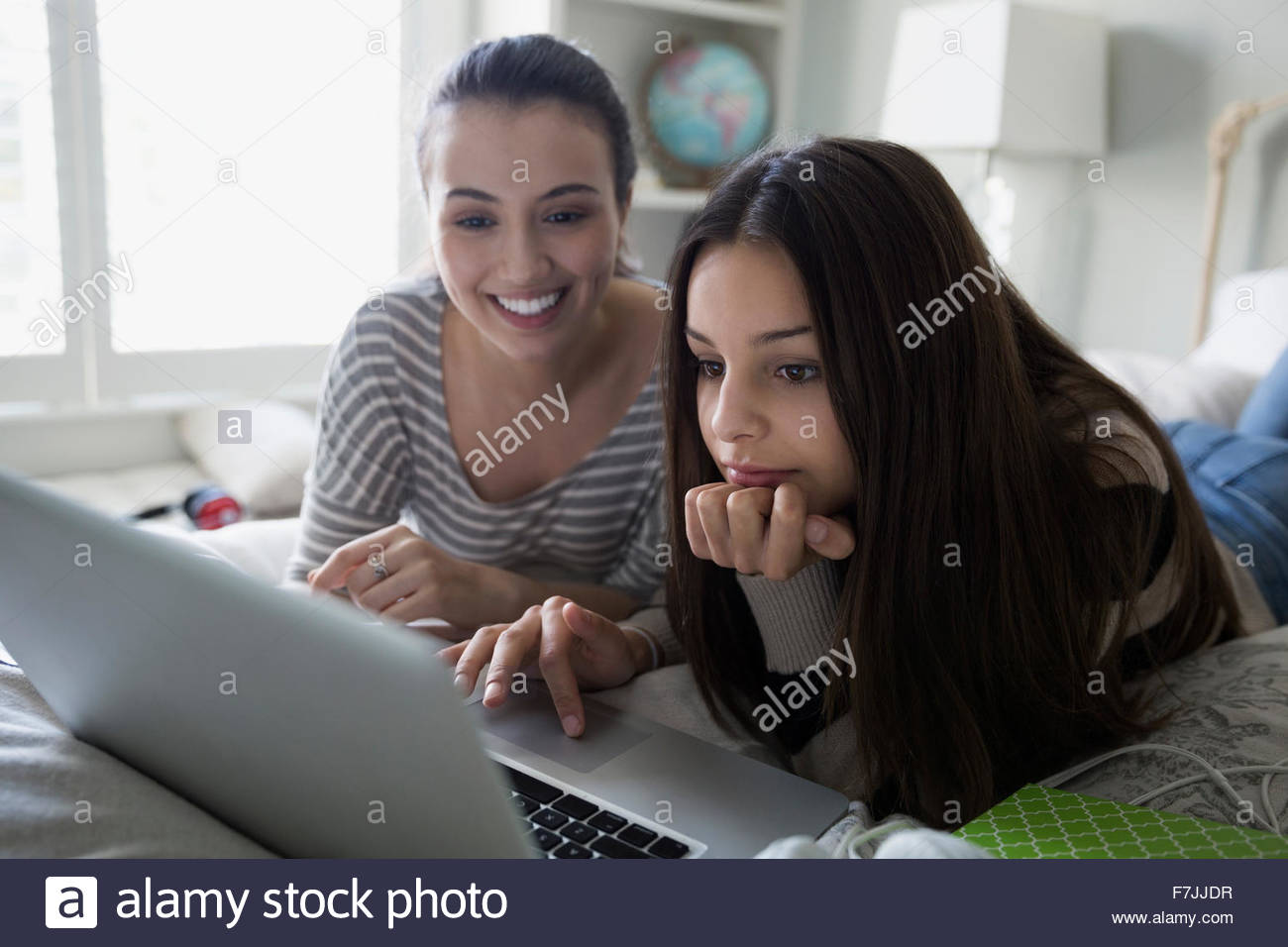 Sisters using laptop on bed Stock Photo
