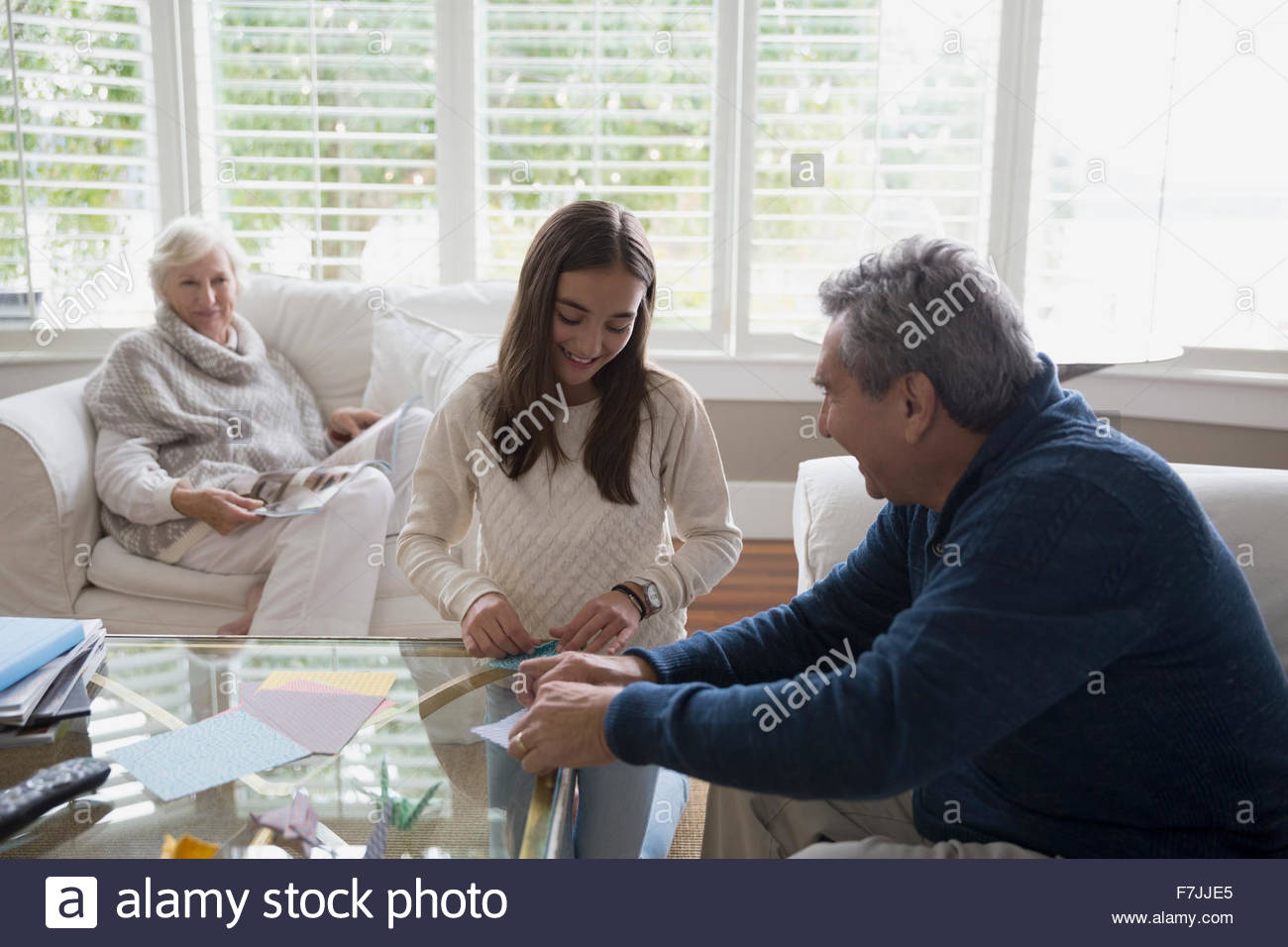 Grandfather and granddaughter making origami in living room Stock Photo