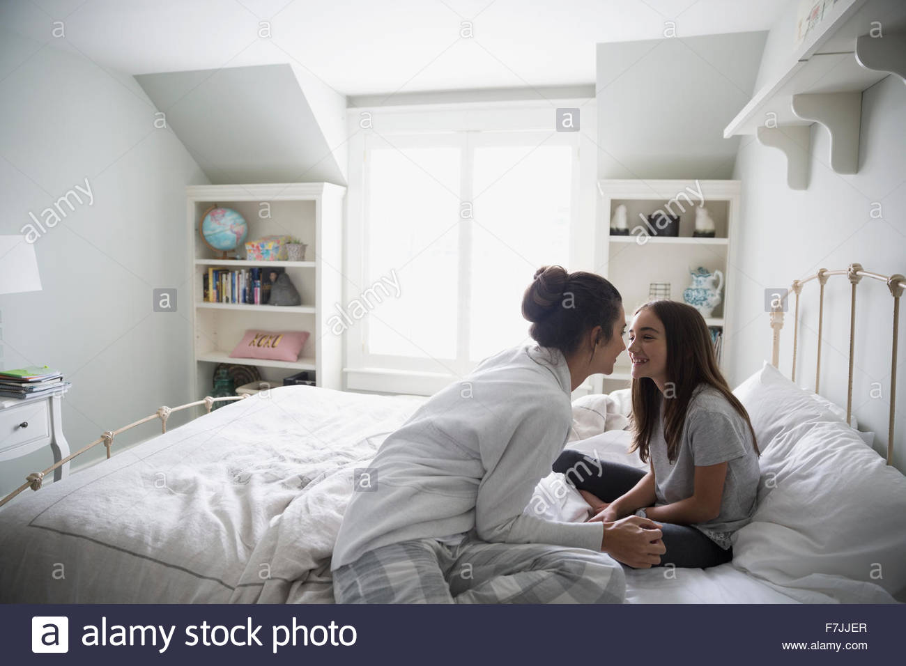 Affectionate mother and daughter rubbing noses on bed Stock Photo