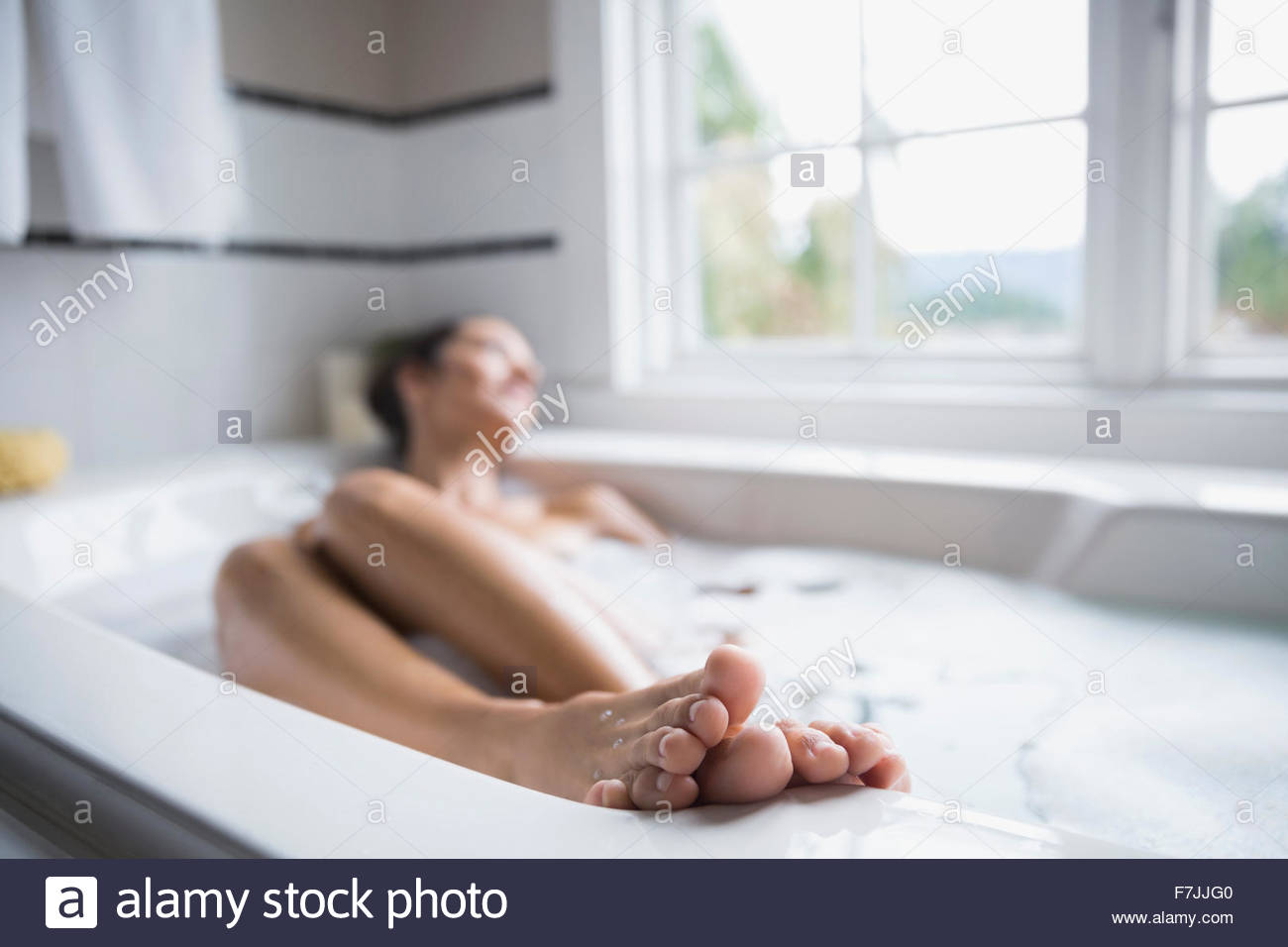 Serene woman with feet up in bubble bath Stock Photo