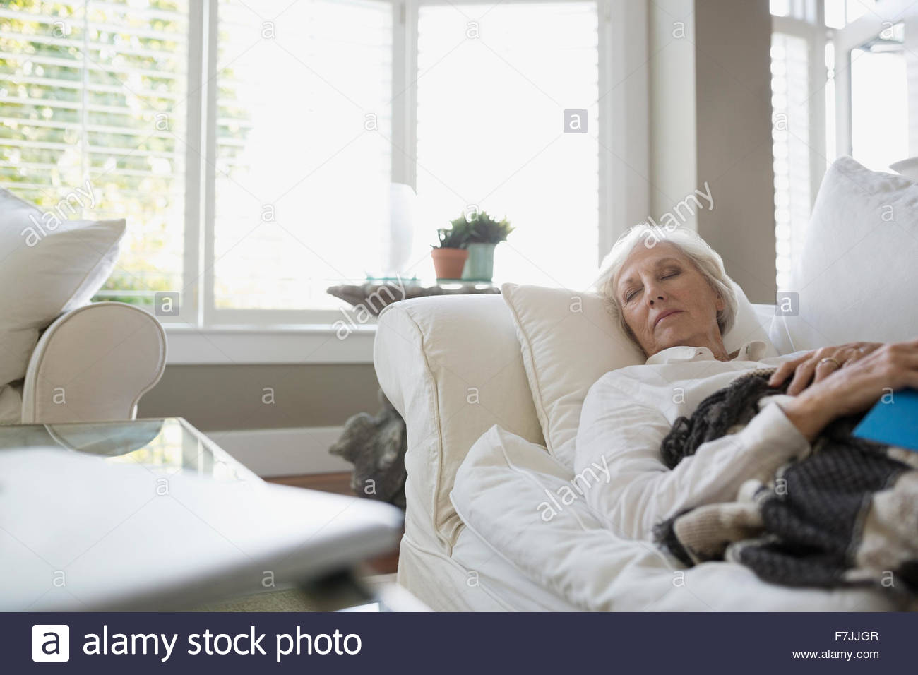 Tired senior woman napping on living room sofa Stock Photo