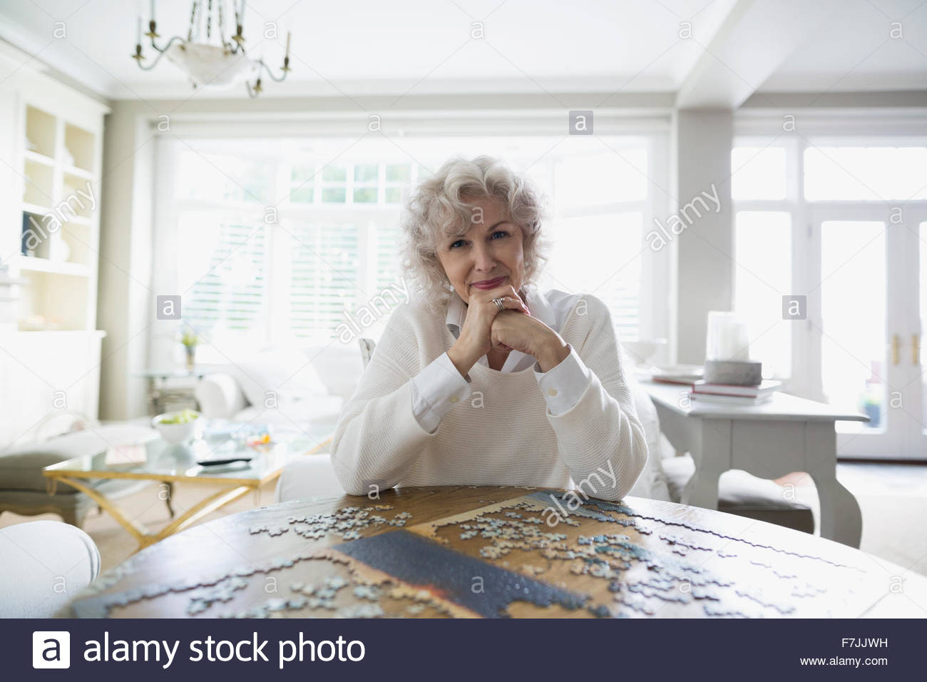 Portrait senior woman assembling jigsaw puzzle dining table Stock Photo