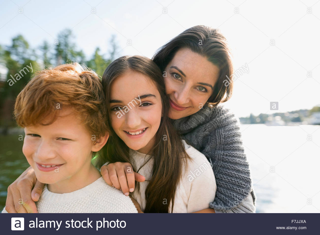 Portrait mother, daughter and son at sunny lakeside Stock Photo
