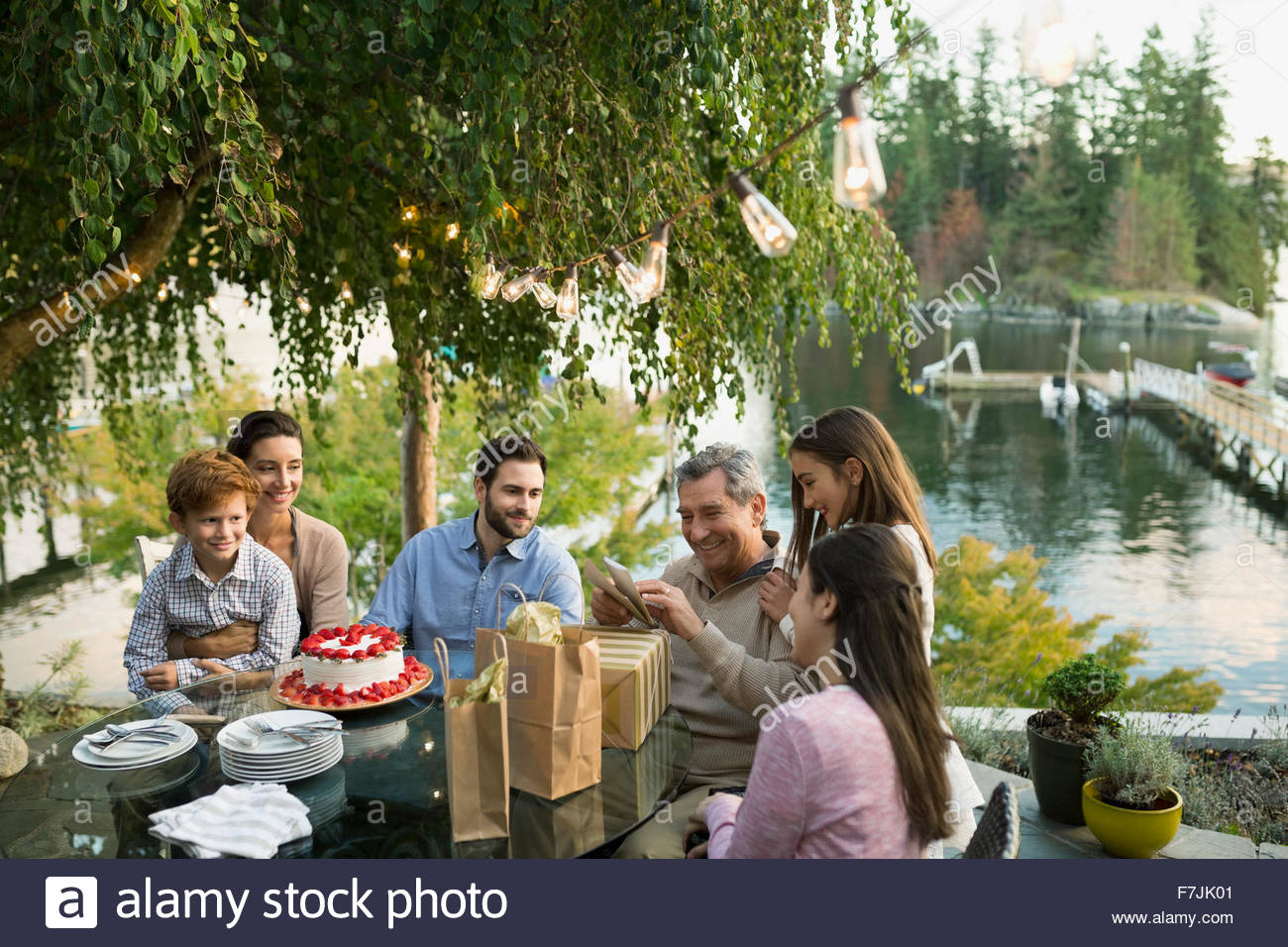 Senior man opening birthday gifts on lakeside patio Stock Photo Alamy