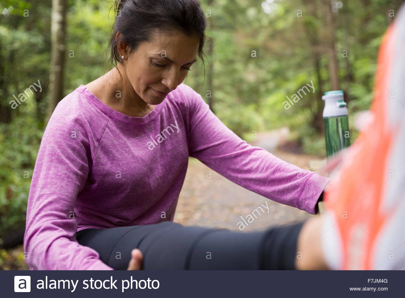 Woman stretching leg preparing for run in woods Stock Photo