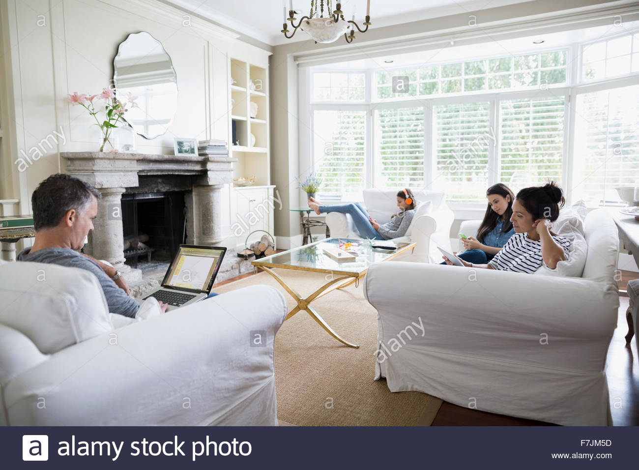 Family using wireless technology in living room Stock Photo