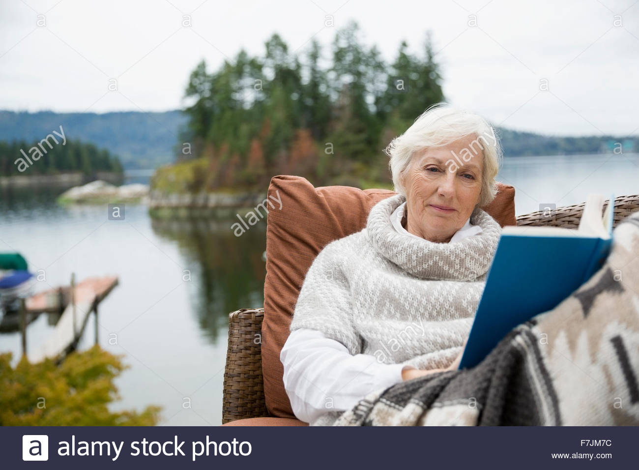 Senior woman relaxing reading book lakeside patio Stock Photo - Alamy