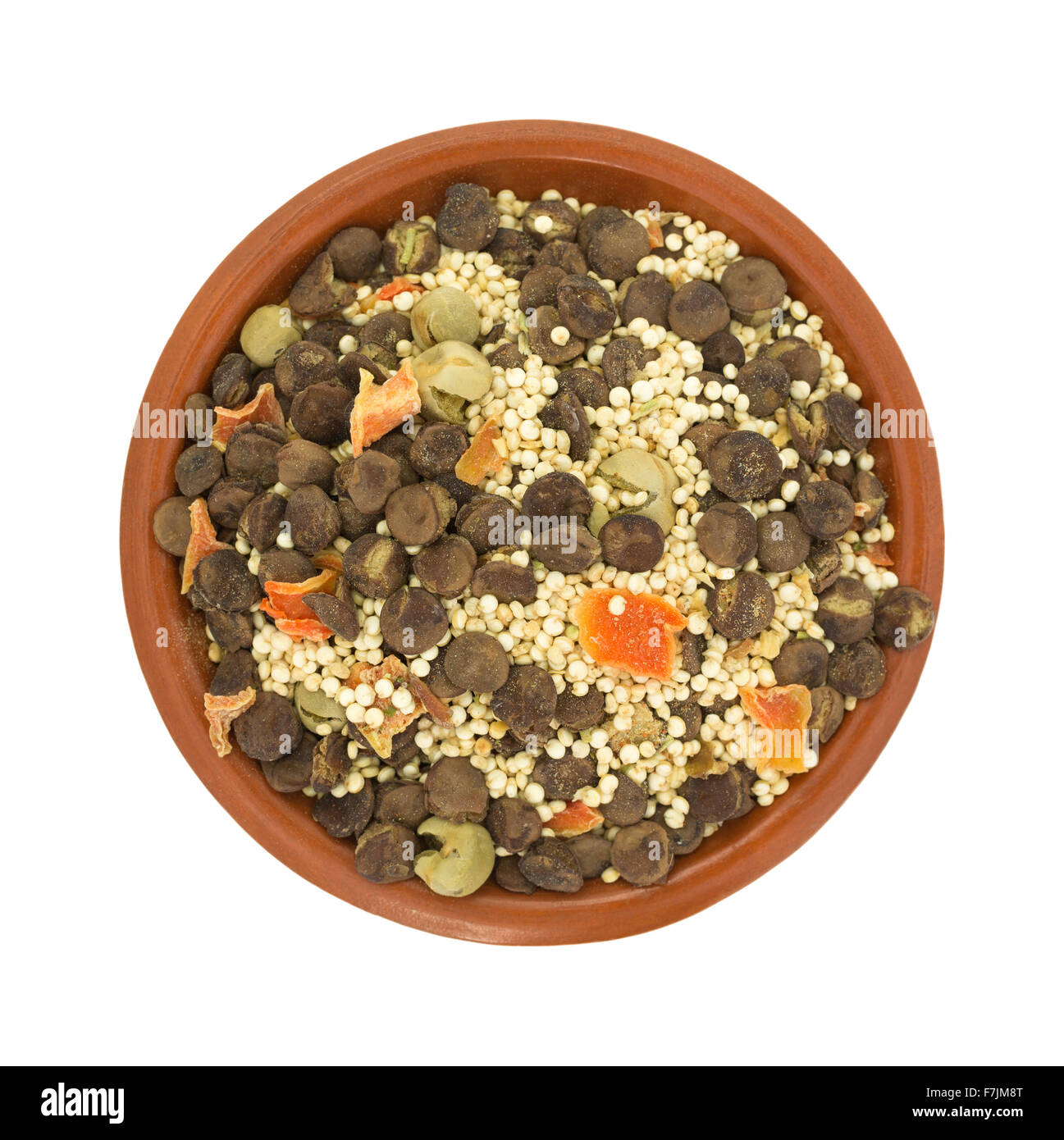 Top view of a small bowl filled with the dry ingredients for quinoa lentil soup isolated on a white background. Stock Photo