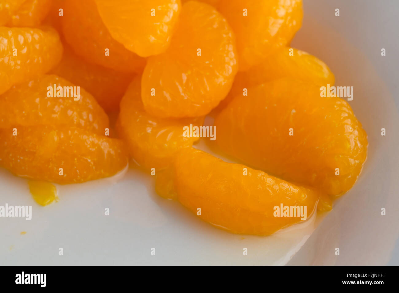 Close view of a serving of canned mandarin oranges in juice on a white