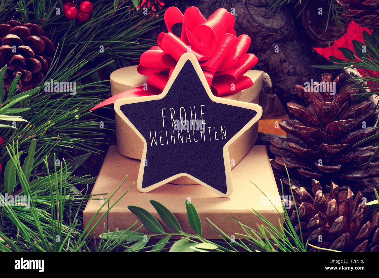 a star-shaped chalkboard with the text Frohe Weihnachten, Merry Christmas in german, on a pile of gifts placed under the christm Stock Photo