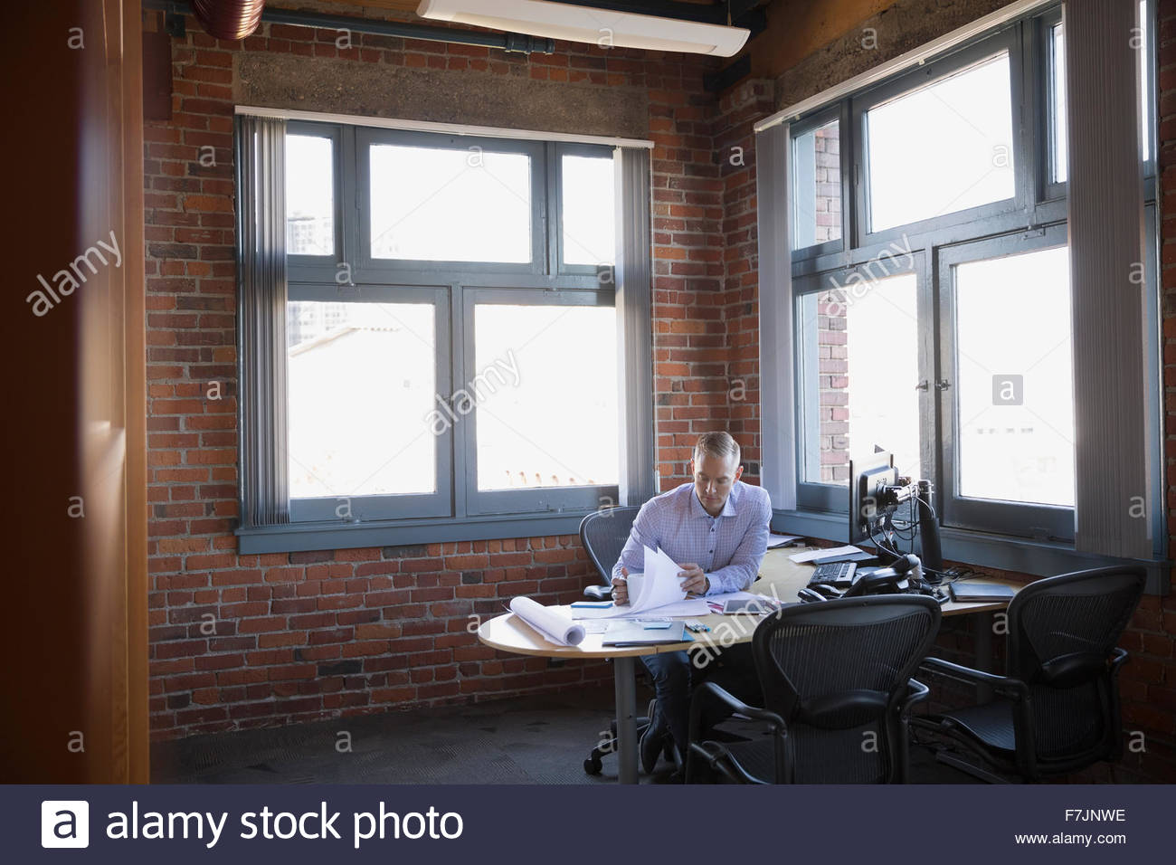 Businessman reviewing paperwork at office desk Stock Photo