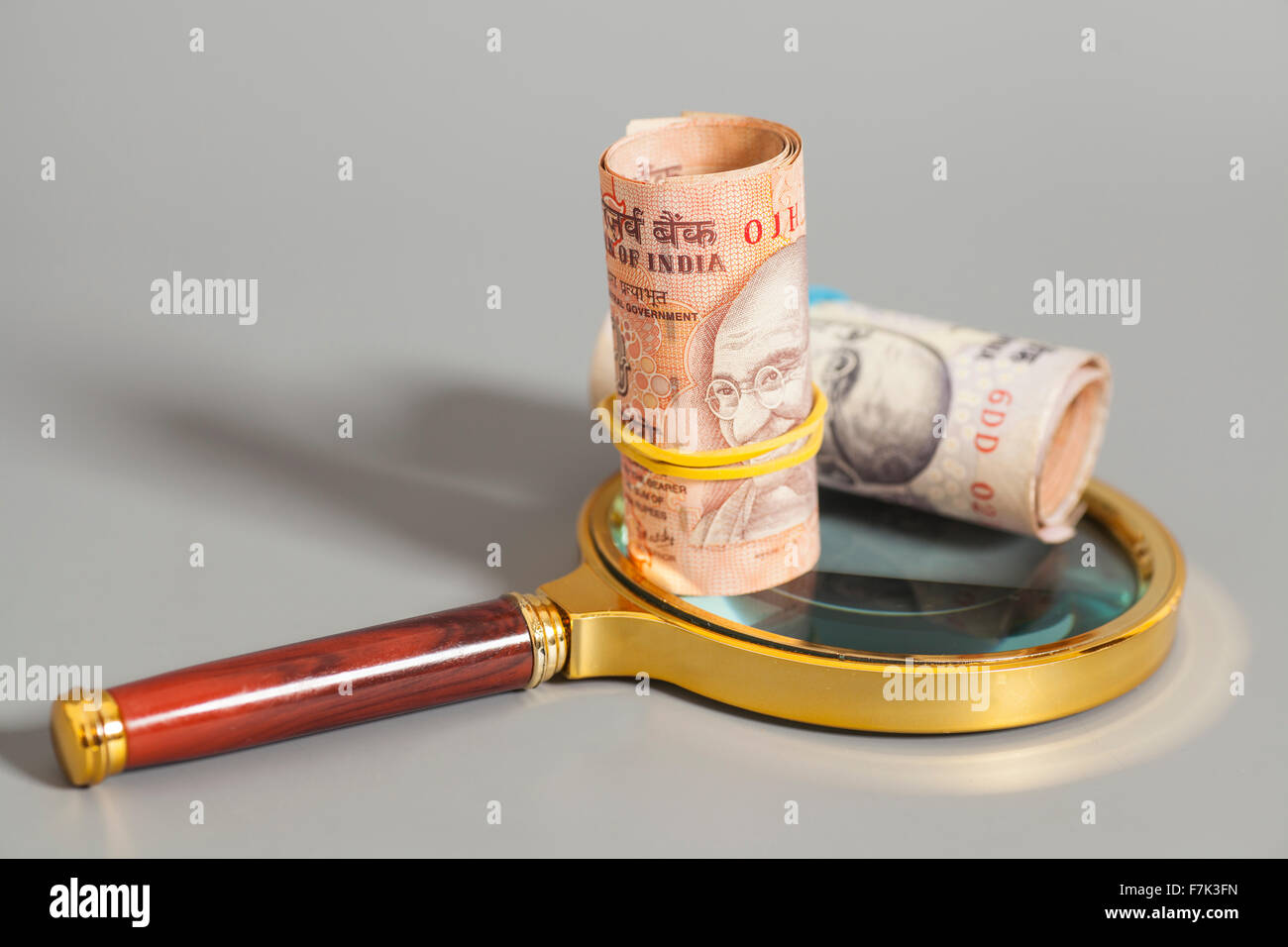 Rolls of Indian Currency Rupee Notes on magnifying glass isolated on ...