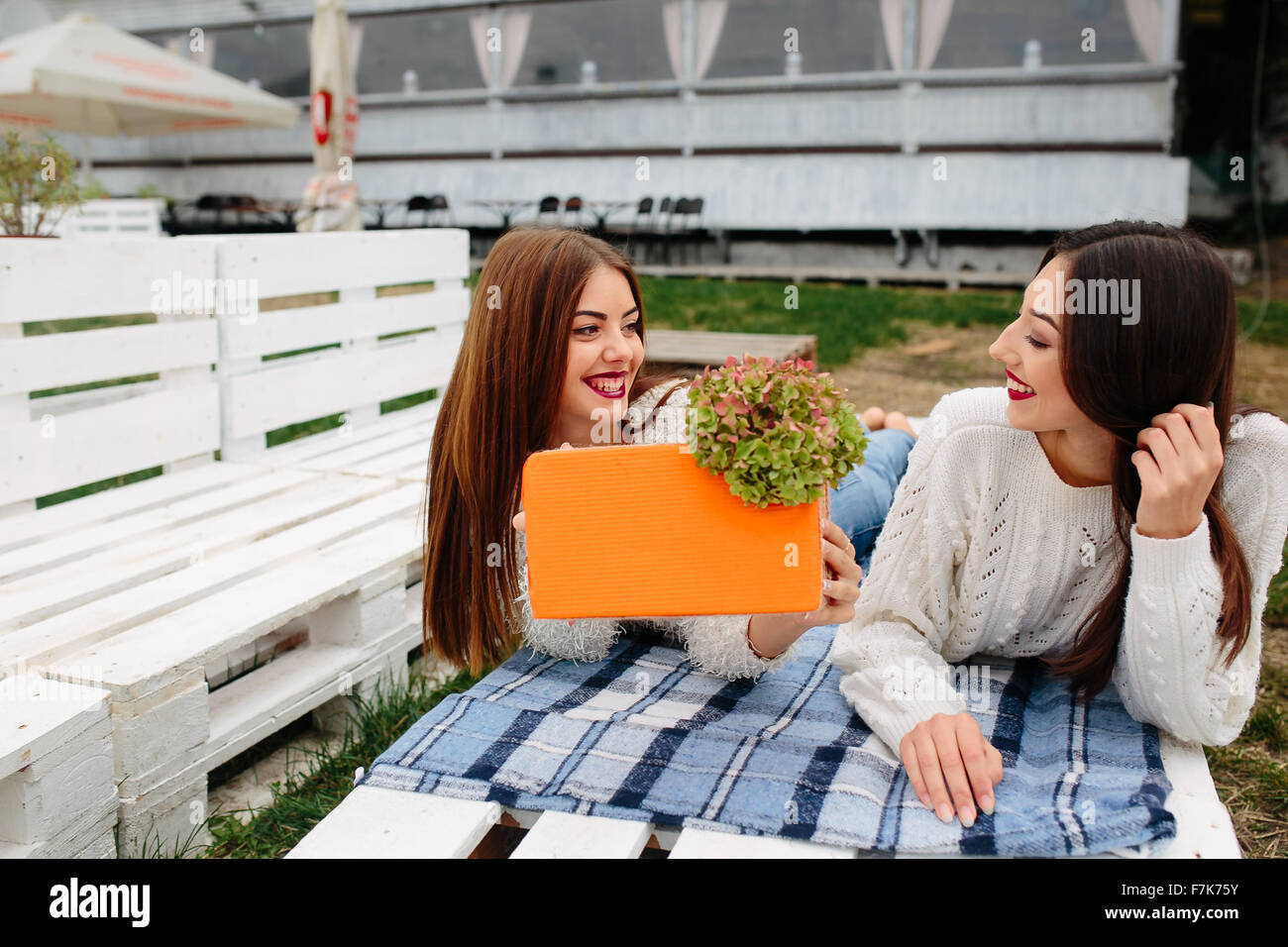 Girls lie on the bench and give each other gifts Stock Photo